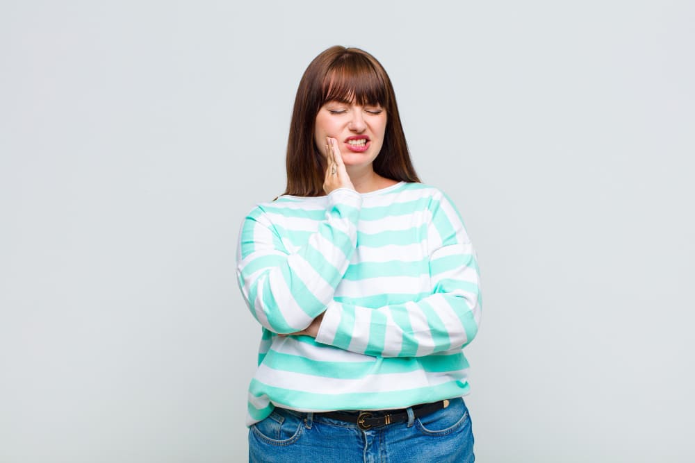 Kobieta w turkusowym swetrze ma bruksizm